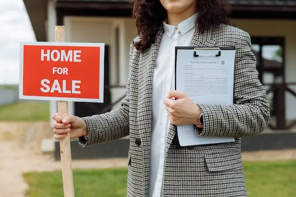 lady holding corflute sign of home for sale in formal clothes